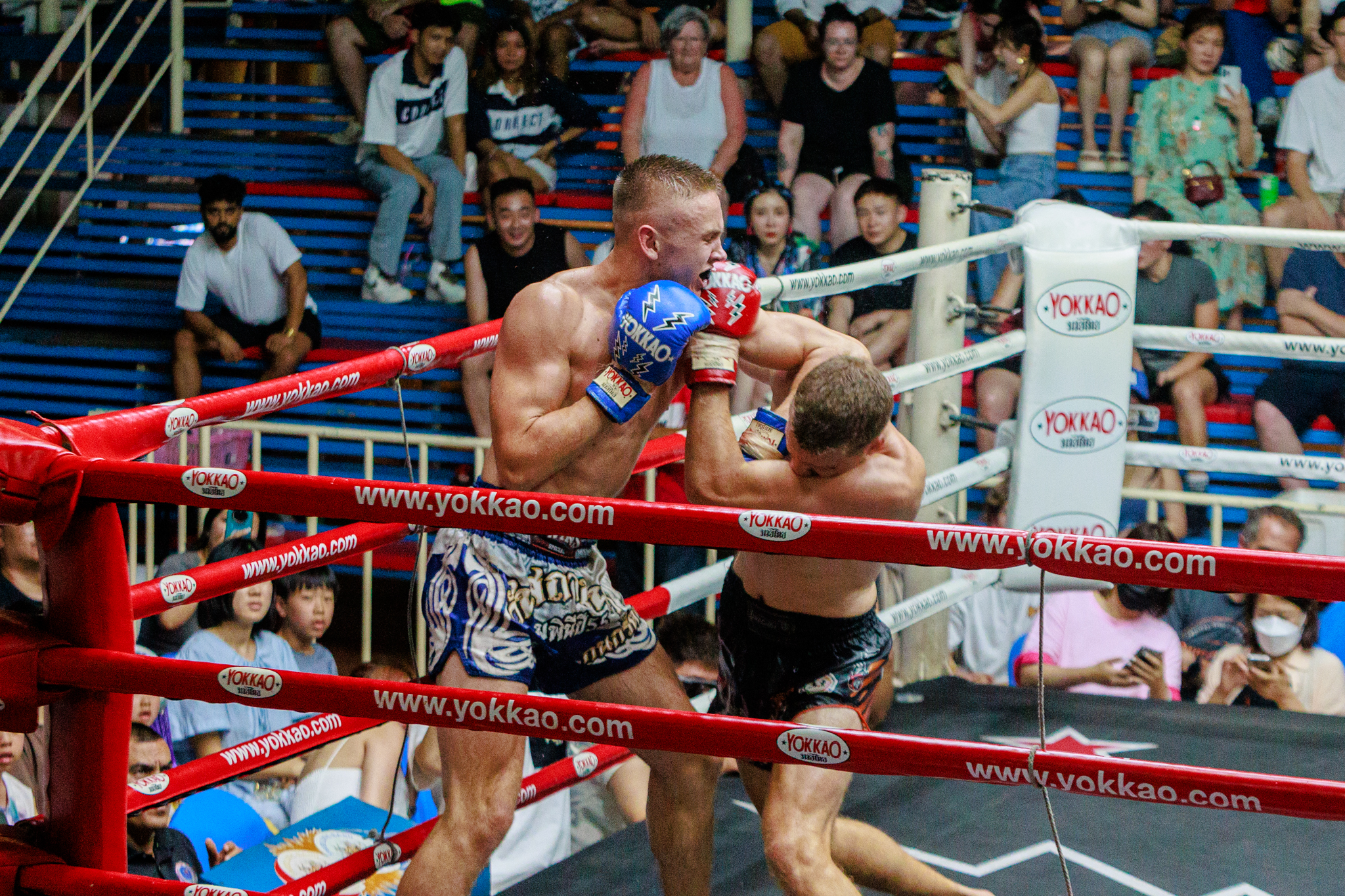 Two Muay Thai boxers are fighting with each other fiercely