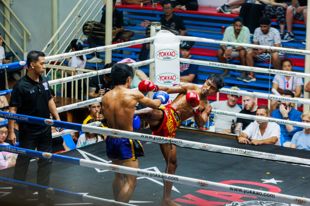 Two men boxing in ring with spectators watching.