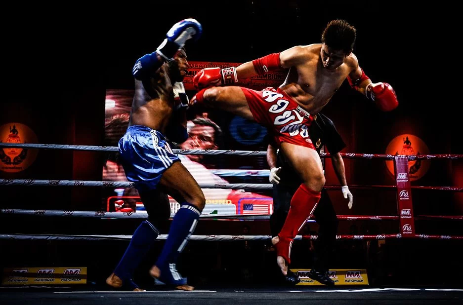 The Red Muay Thai Fighter is Kicking the Blue Opponent