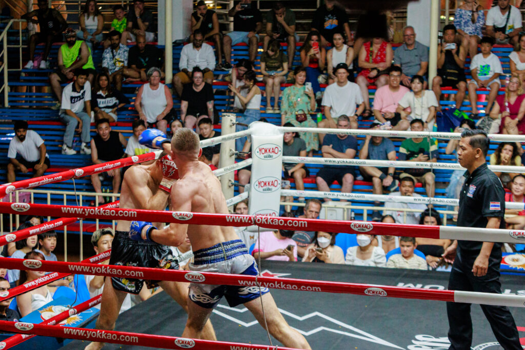 Two boxers fiercely battling in a ring, while a captivated crowd watches their every move.