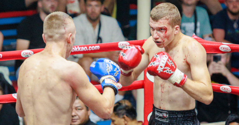 Image of two men in boxing ring, one man wearing red gloves, in Authentic Muay Thai Fight.