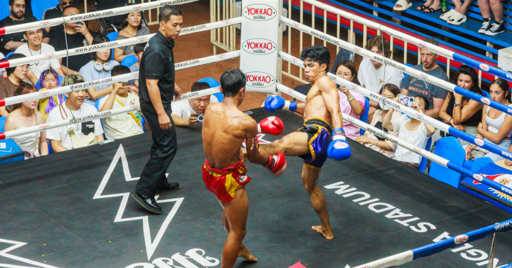 Muay Thai fighters in ring with crowd watching the intense match