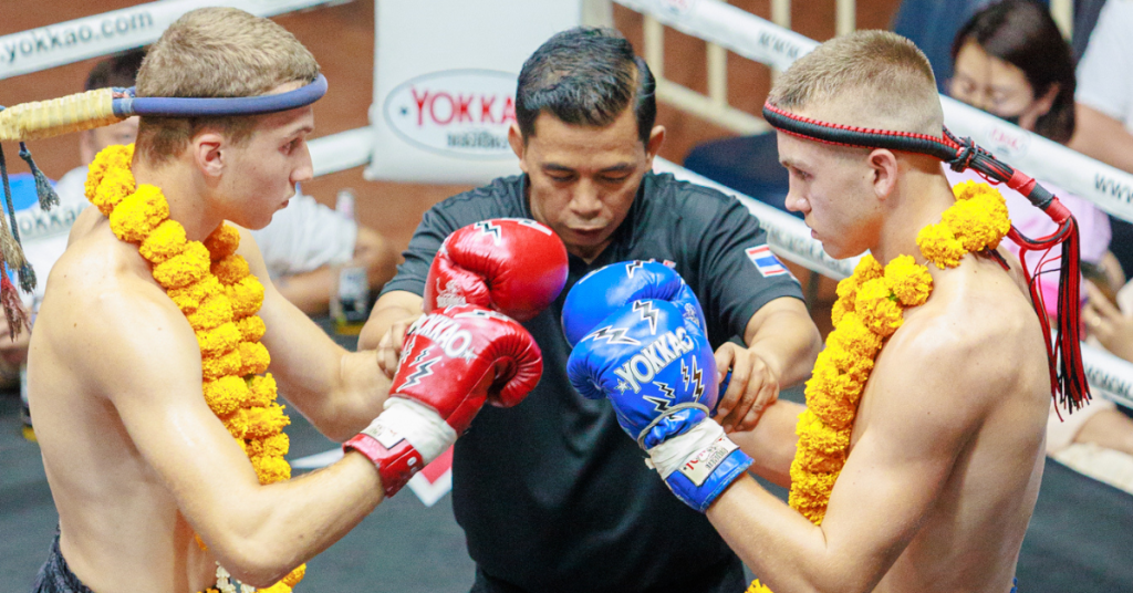 Two men wearing boxing gloves and a referee in the background