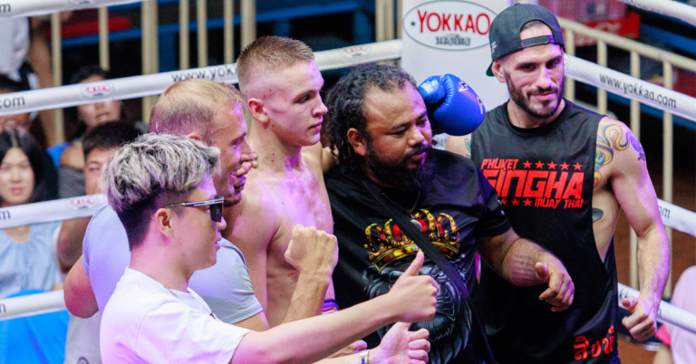 A man receives congratulations from his opponent in a Muay Thai boxing ring, showcasing sportsmanship and respect