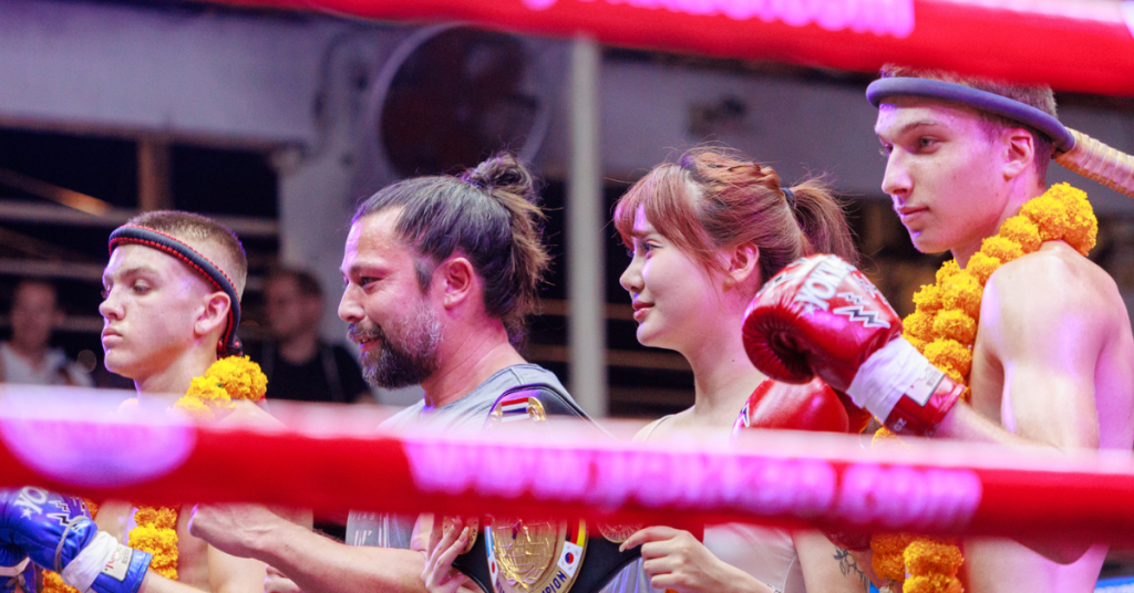 A team of athletes poses in a boxing ring, demonstrating their dedication to the sport of Muay Thai